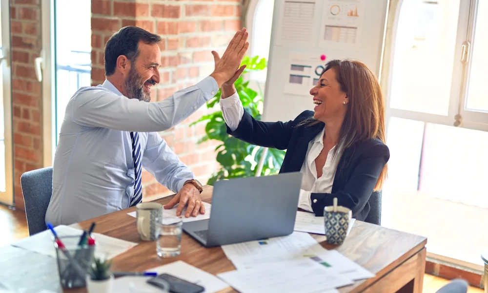 Two business owners celebrating funding approval despite adverse credit