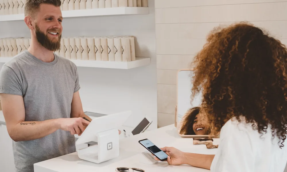 A card payment at a retail counter, contrasting a Merchant Cash Advance with invoice finance